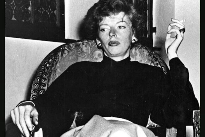 Medium_black-and-white-marjorie-cameron-sitting-on-a-chair-glaring-to-the-distance-holding-a-lit-cigarette